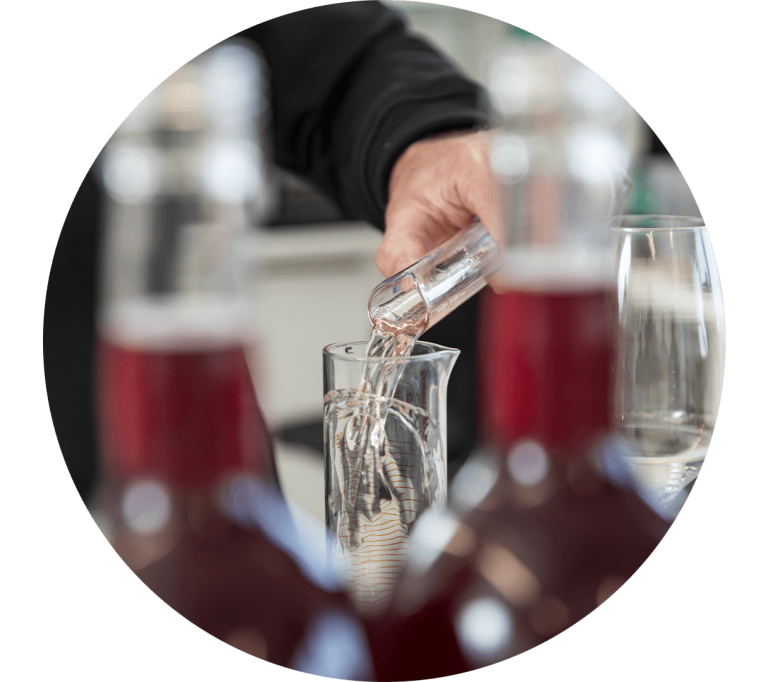 Szene aus dem Weinlabor: Wein wird von einem in das andere Reagenzglas gegossen.